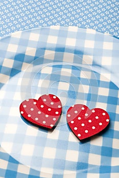 Red hearts lying on blue vintage plate with spoon