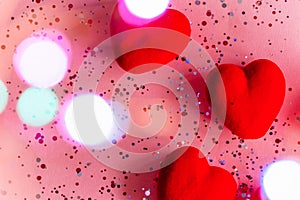 Red hearts on pink background with confetti and bokeh. Valentine's Day Template