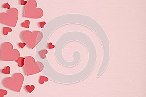 Red hearts on soft pink paper color background.