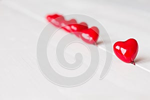 Red hearts are on white wooden background. St. Valentines background. One heart in the foreground and other are not in fokus