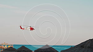 Red Helicopter Flies Low Over The Sea Near The Beach In The Tropics. Fire Helicopter Flies. 4K Video