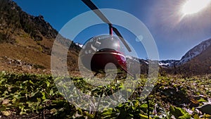 Red helicopter stands parked in the mountains on the meadow