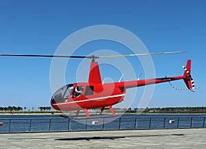 A red helicopter is taking off at a seaside resort photo