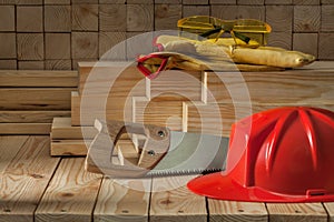 Red helmet handsaw gloves goggles construction carpentry tools on wooden background