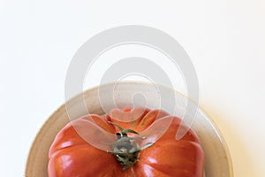 Red heritage tomato, organic, on a shallow plate, isolated on white