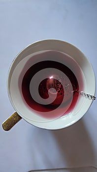 red hibiscus tea in a cup with a strainer, drink