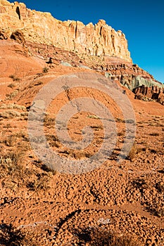 Red Hills of Eroded Sand and Clay Below the Steep Cliffs of the Waterpocket Fold