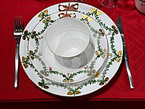 Red holiday table setting with plates and silverware.