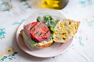 Red homemade vegan beetroot hamburger seen on table with salad and bread. Beet are used as a substitute to meat