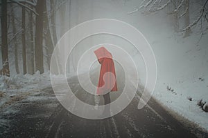 Red hooded woman in a desolate winter road