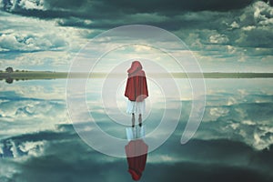 Red hooded woman in a strange landscape with clouds