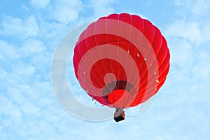 Red hot air balloon against blue cloudy sky