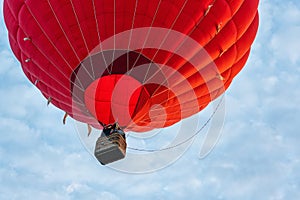 Red hot air balloon against blue cloudy sky