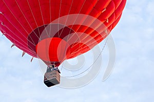 Red hot air balloon against blue cloudy sky