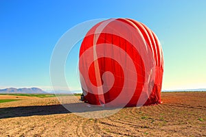 A red hot air balloon being dismantled