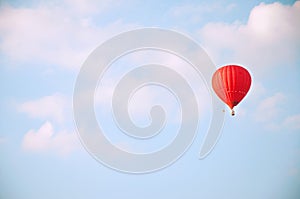 Red hot air balloon in blue sky with white clouds