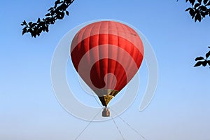 The red hot air balloon rides in the blue sky