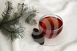 Red hot aromatic tea made from forest fruits or herbal or apples or red fruits in the glass cup on a white blanket.