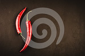 Red hot Chile pepper on a dark stone background/two red hot Chile pepper on a dark stone background. Top view. Copy space