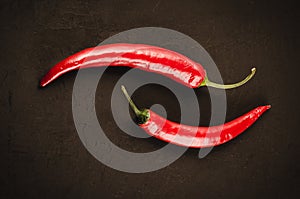 Red hot Chile pepper on a dark stone/two red hot Chile pepper on a dark stone background