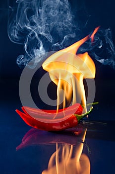 Red hot chili pepper on black background with flame