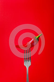 Red Hot Chili Pepper on Fork with Smoke on Red Background