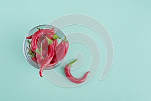 Red hot chili pepper in glass bowl on green background