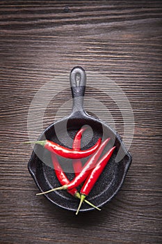 Red hot chili pepper in pan on wood background