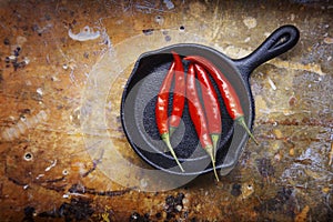 Red hot chili pepper in pan on wood background