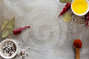 Red hot chili pepper pods peas, salt, oil and bay leaves on grey vintage metal culinary background