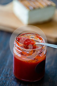 Red Hot Chili Pepper Sauce for Artisan Cheese made with Vinegar and Sugar in Glass Bowl with Spoon