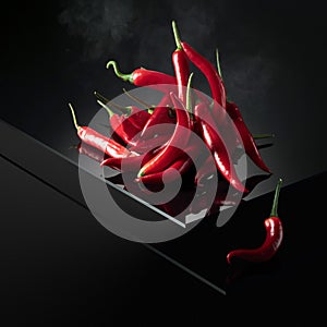 Red hot chili pepper with smoke on a black reflective background