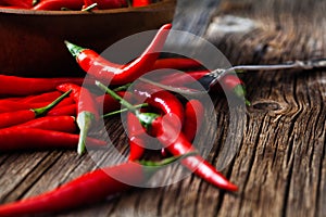 Red hot chili pepper on vintage silver fork over wooden background