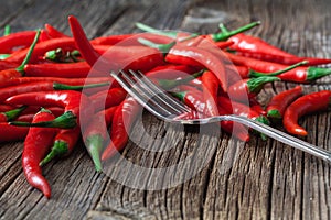 Red hot chili pepper on vintage silver fork over wooden background