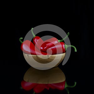 Red hot chili pepper in a wooden bowl on a black background. Photo