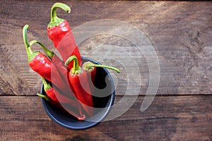 Red hot chili peppers in the bowl on wooden table background. Top view, copy space