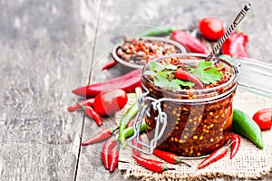 Red hot chili peppers marinated in a glass jar on wooden backgr