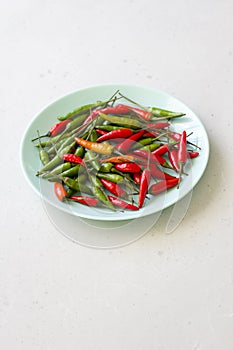 Red Hot Chili Peppers On Modern Background or White Table, on a Round Plate. A Lot of Red Chilli Peppers. Green Hot Chili Peppers