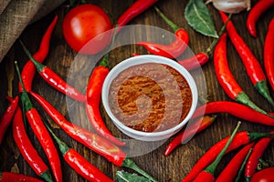 Red hot chili peppers and salsa or adjika in white ceramic bowl.