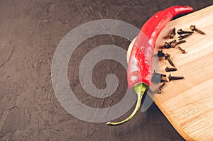 Red hot chili peppers and spices on a empty cutting board/Red hot chili peppers and spices on a empty cutting board on a dark