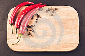 Red hot chili peppers and spices on a empty cutting board/Red hot chili peppers and spices on a empty cutting board on a dark