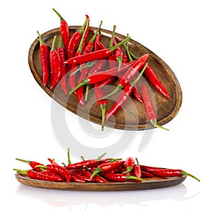 Red hot chili peppers on a wooden plate isolated on white background.