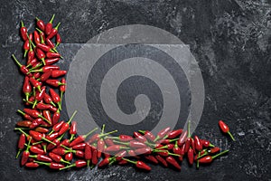 Red hot chilli peppers angle frame on a black table and black rock chopping desk, top view with copy space