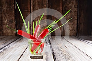 Red hot chilli peppers and green onions in glass of water