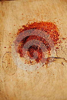 Red hot chillies pepper flakes on wooden board background