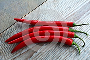 Red hot chilly peppers are lying on the wooden background. Ready to eat