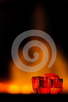 Red hot coal bars in focus on dark background with flames. Background of raw coal with soft focus exclusion with color