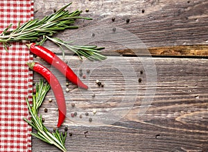 Red hot pepper and rosemary on the rustic wooden background