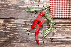 Red hot pepper and rosemary on the rustic wooden background