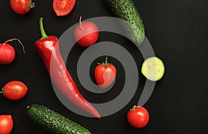 Red hot pepper, small tomatoes and cucumbers on a dark background